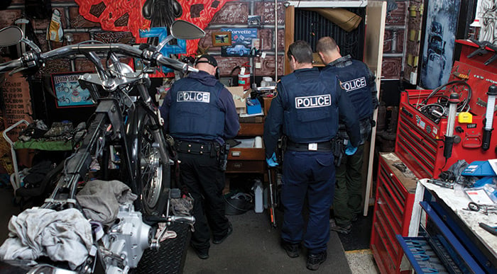 Three police officers searching a work shop