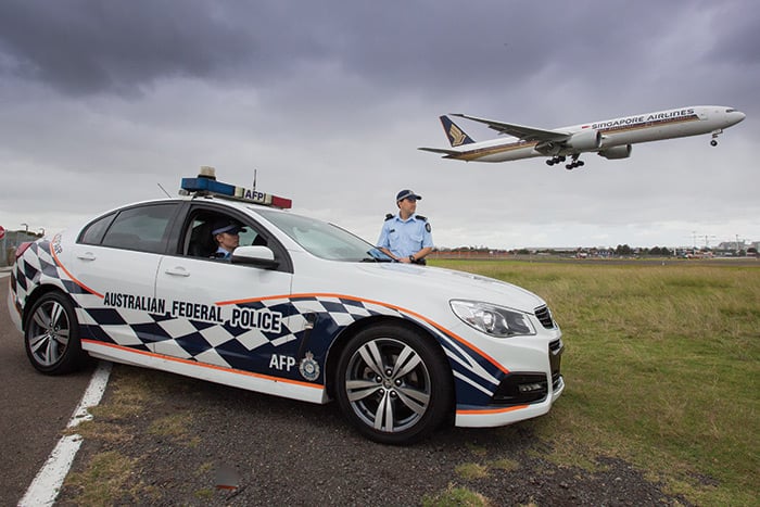 An AFP vehicle and two officers with a plane taking off in the background