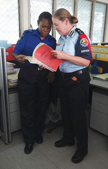 A Papua New Guinea officer and AFP officer reading a file