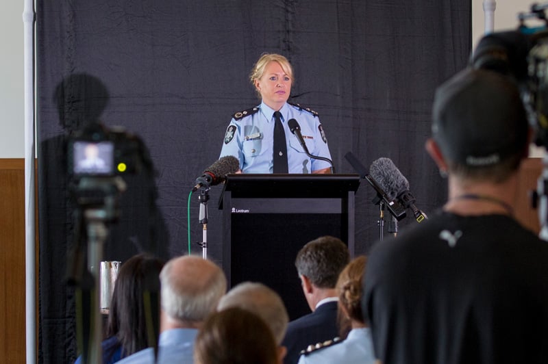 A female police officer standing at a lecturn speaking