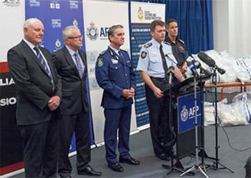 AFP Commissioner Andrew Colvin delivering a media statement at a lectern flanked by representatives from partner agencies.