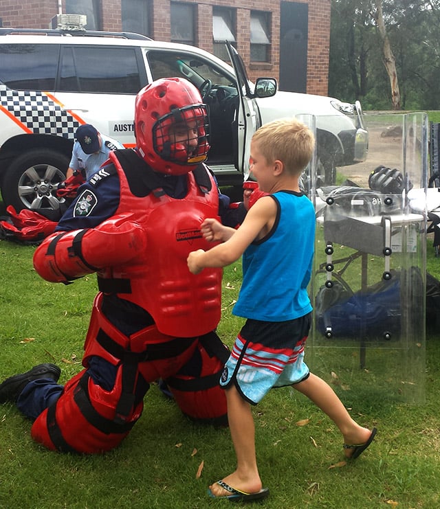 A police officer wearing red protective armour playing with a young boy