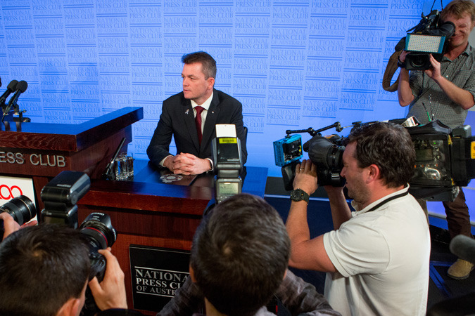 AFP Commissioner Andrew Colvin sitting at a desk surround by media
