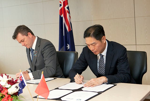 two men sitting next to each other at a desk signing documents