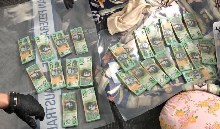 AFP officers lay out piles of $100 bills on evidence bags.