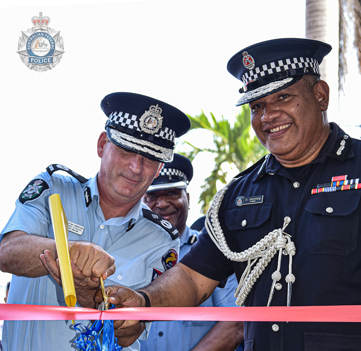 An AFP and PNG police officer cut a red ribbon