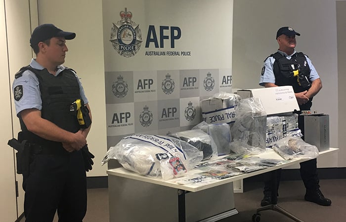 Two AFP officers stand by a table of seized items