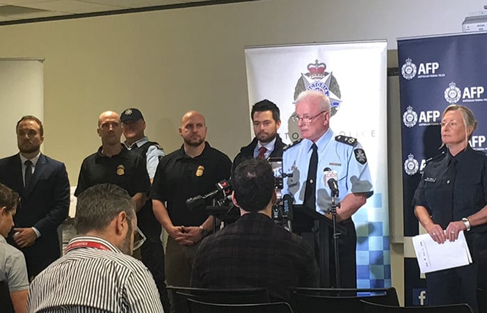 A man speaking to the media surrounded by other law enforcement members
