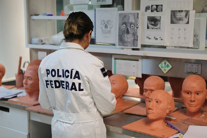 A female in a white jumpsuit with multiple reconstructed faces for forensic use