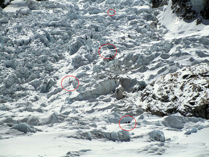 People climbing through an icefall, the picture taken from a distance to reflect how small people are in comparison to the area they are climbing