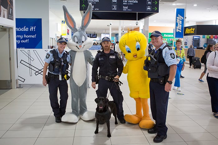 three police officers and a police dog pose with cartoon characters bugs bunny and tweety bird