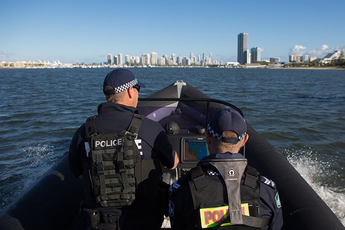 two police officers on a boat with high rise buildings in the distance