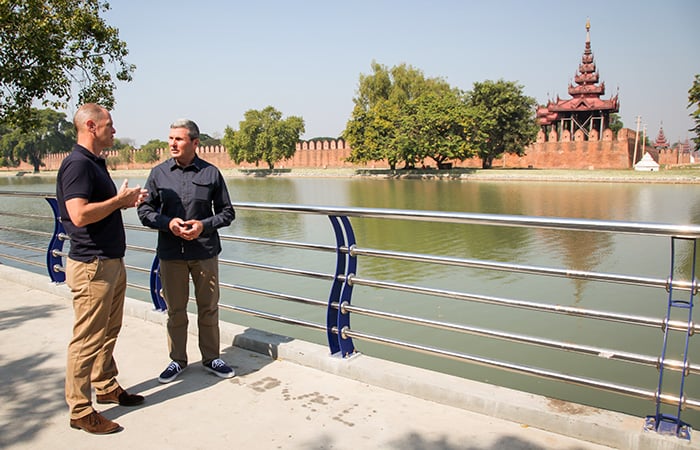 two men standing next to a river talking