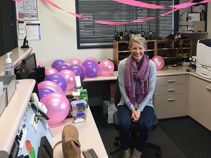 A female sitting at an office desk decorated with balloons and streamers