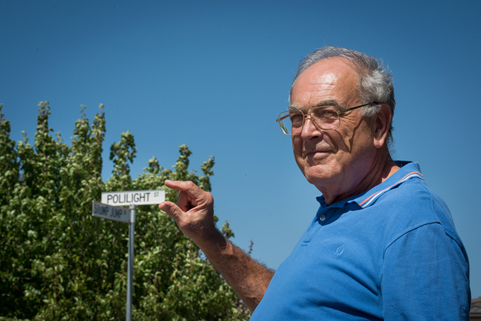 A man standing close to the camera with a street sign in the background