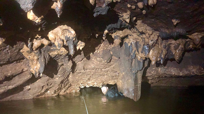 A low cave roof with a diver barely above water