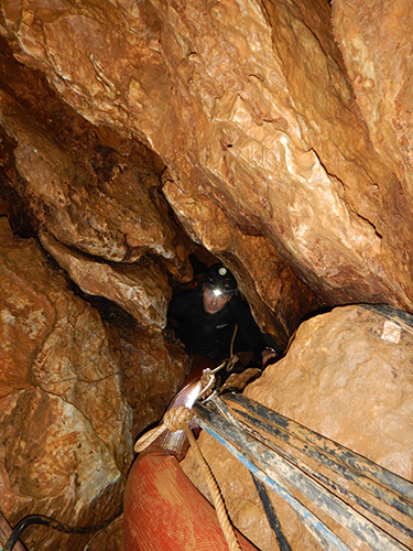 A man inside a narrow chamber in the cave