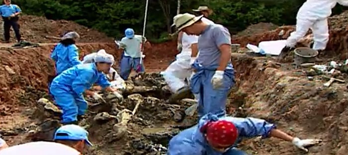 Workers collecting evidence at a mass grave site