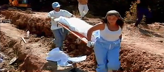 Two people carrying a stretcher with a body covered by a white sheet