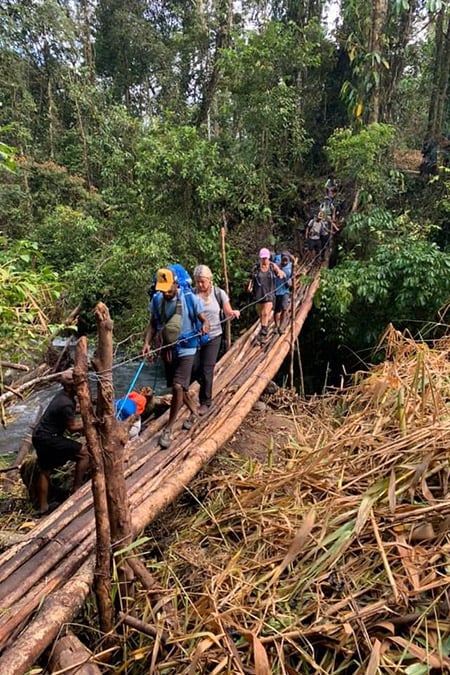 People crossing a bridge made of tree logs