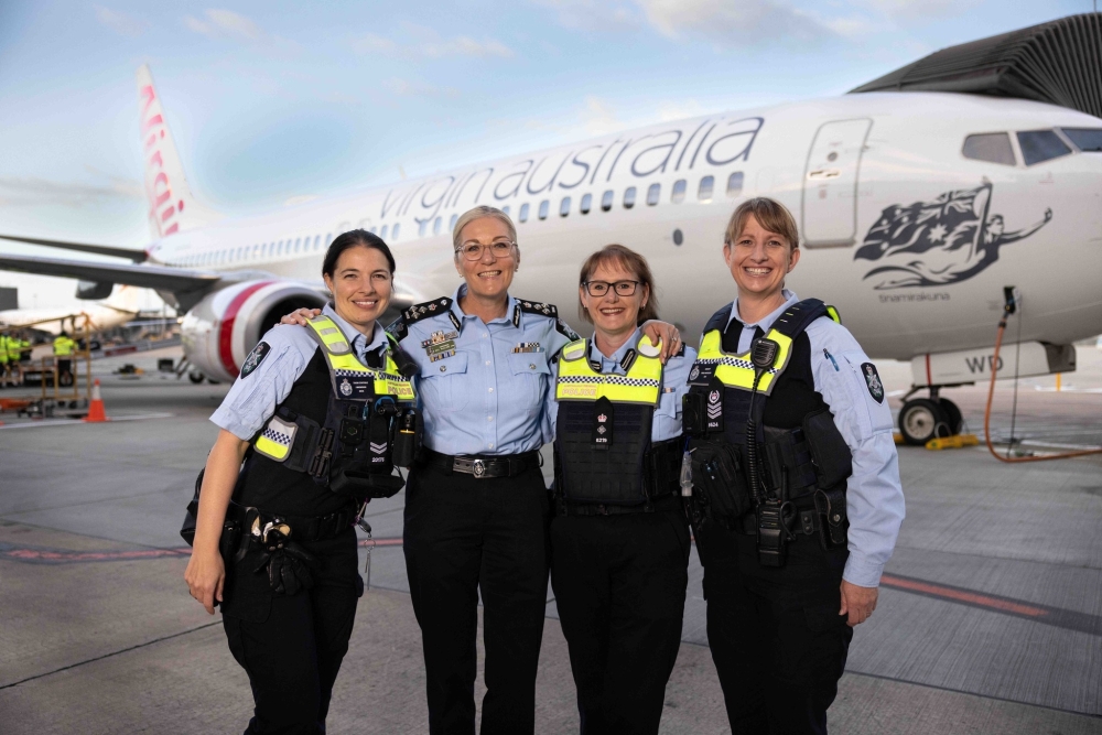4 policewomen in front of plane celebrating International Women's Day