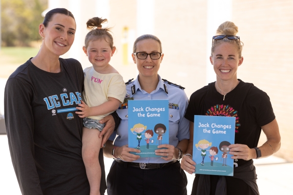 Uniformed police officer with two members of the public holding a child prevention fiction book