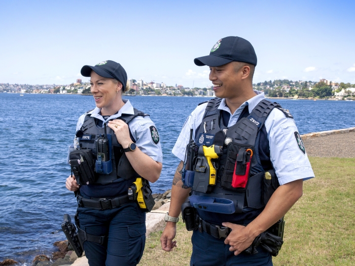 Two police officers walking alongside a lake