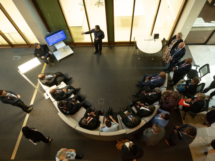A bird's eye view of a person presenting to a group of people sitting on a couch in a semi-circle