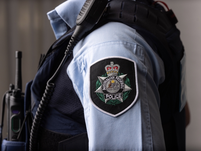 Close up of an AFP police officer standing side on focussing on the AFP badge