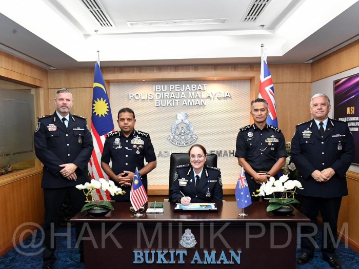 Three AFP officers and two RMP officers stand behind a wooden desk