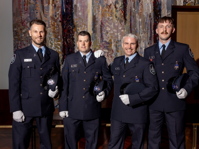 Four newly-graduated AFP officers in navy blue tunics stand in Parliament House