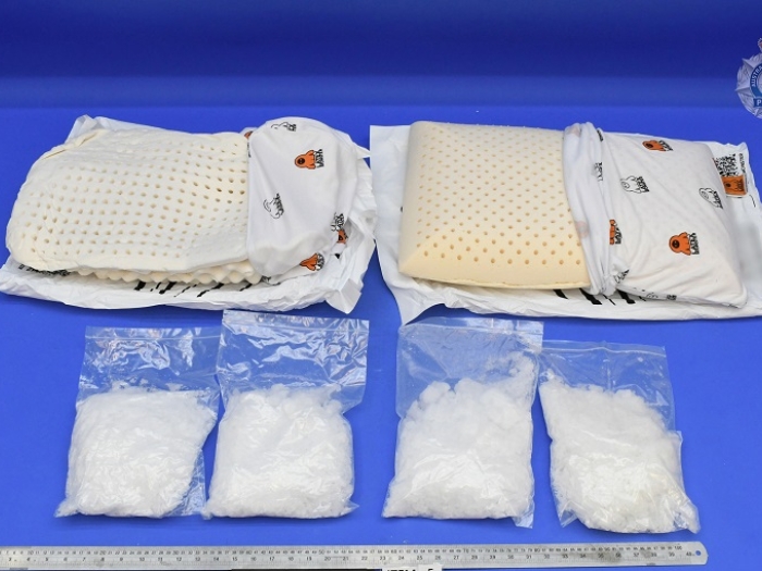 Two partially deconstructed pillows lay behind four clear bags containing methamphetamine.