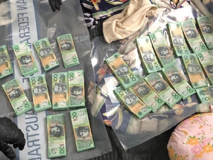 AFP officers lay out piles of $100 bills on evidence bags.