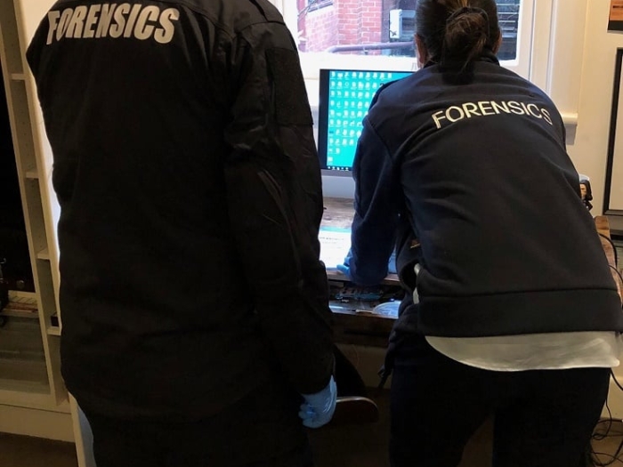 Two forensic specialists examining a computer