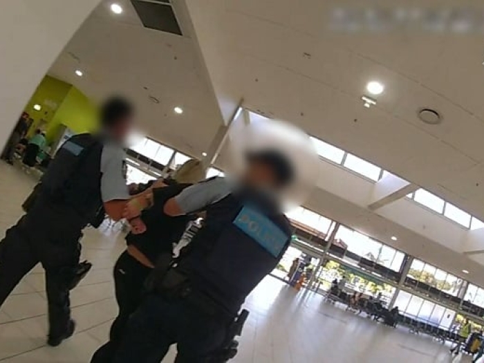 Two police officers lead a woman in black clothing out of the airport terminal