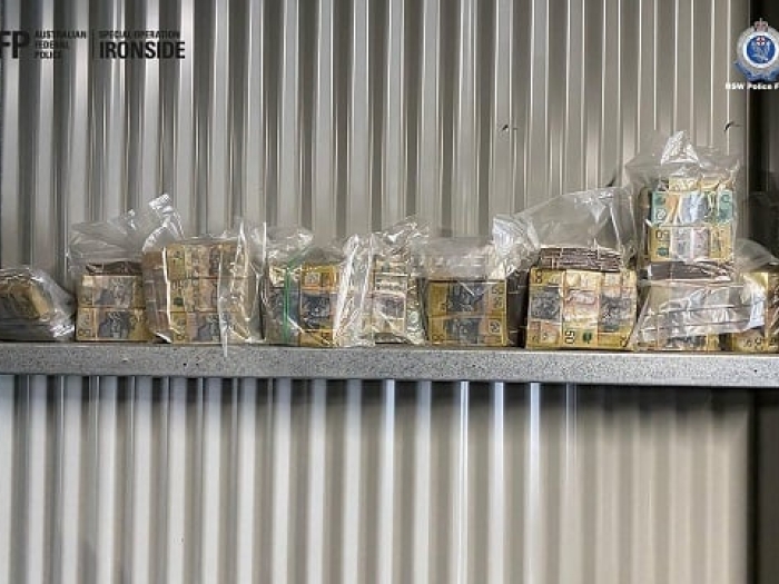 Cash in plastic bags lined up against a metal wall