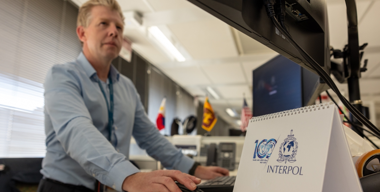 AFP member at a computer next to an Interpol sign