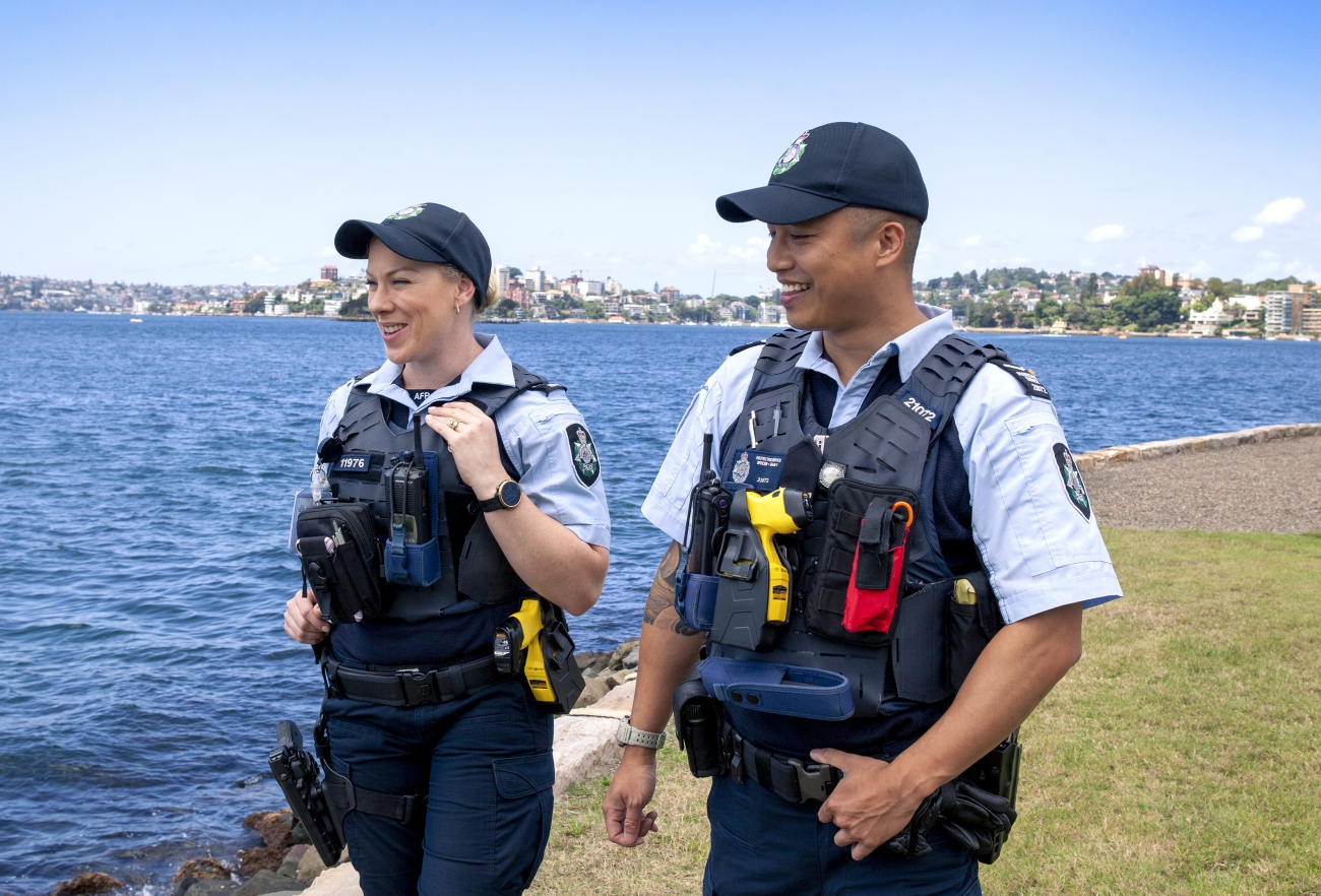 Two police officers walking alongside a lake