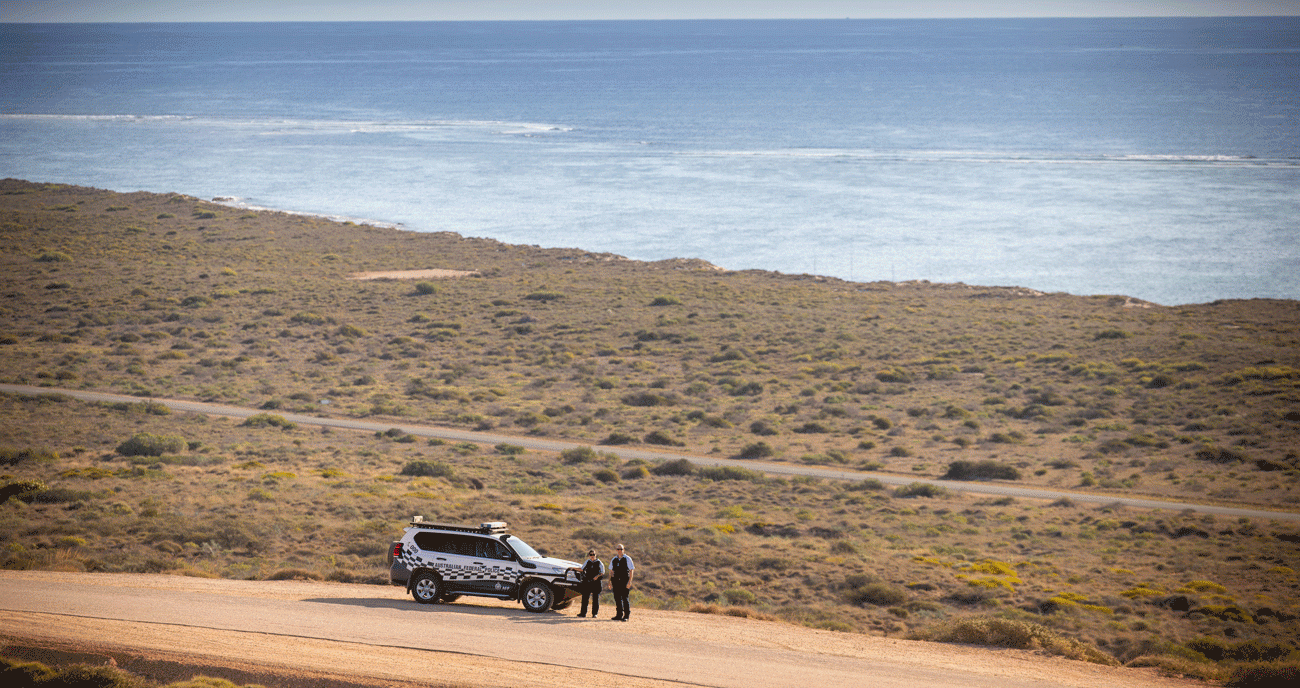 PSO's stood in front of their AFP four wheel drive with ocean behind them